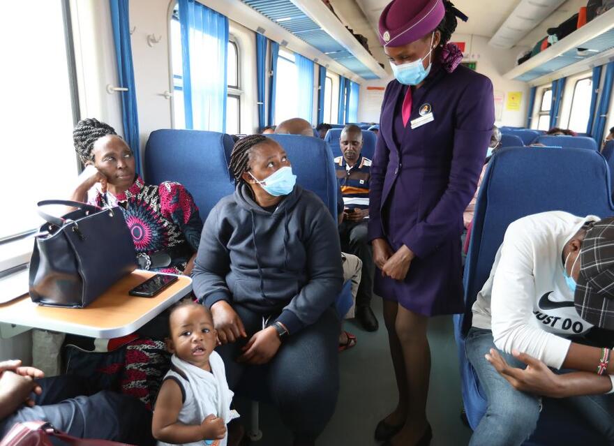 　　7月29日，列車員菲奧娜（站立者）在蒙內鐵路客運列車上與乘客交流。新華社記者董江輝攝
