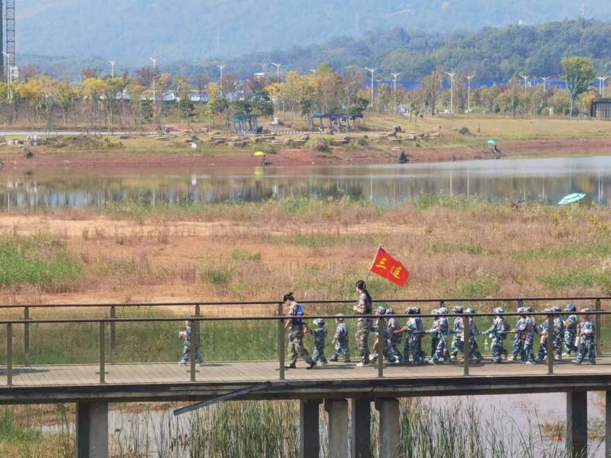 10月24日，秋游的幼儿园小朋友在老师带领下走在清水塘公园里的木桥上。本报记者 常雯宜摄