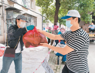 武汉市东西湖区长青街三民小区居民（右）在购买团购菜。 　　新华社记者 肖艺九摄