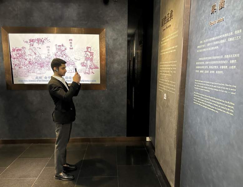 10月23日，2023“一带一路”媒体合作论坛联合采访团团员在中国酒文化城认真观看展览。本报记者 刘书文摄